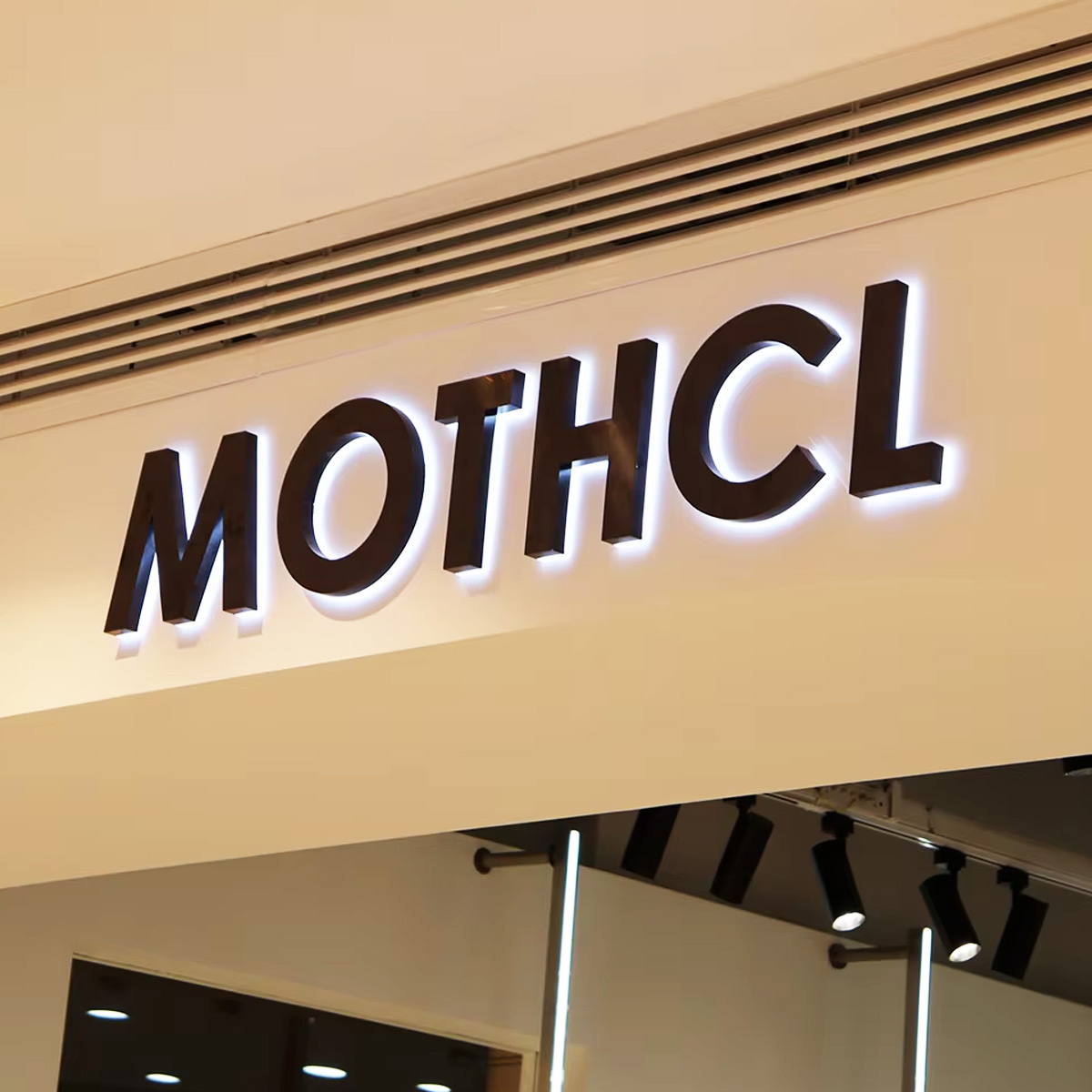 Indoor backlit shop signage in Dubai with black 3D letters and white LED halo illumination